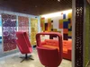 A space in our Mexico City office, with hanging panels featuring cut-outs inspired by papel picado, an orange couch and red chairs.