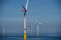 Im Vordergrund des Bildes ist ein großes Windrad zu sehen, und dahinter aufgrund der Perspektive viele kleine in der Nordsee.