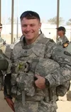 Dennis smiling in his military uniform and holding his helmet