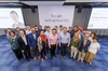 A group of people stand and smile at the camera with the Google Skills Ignition signage behind them.