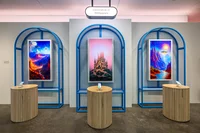 Carousel of four photographs. The first photo shows the demo room for Gen AI Wallpapers with three screens, each screen shows a different generated wallpaper.