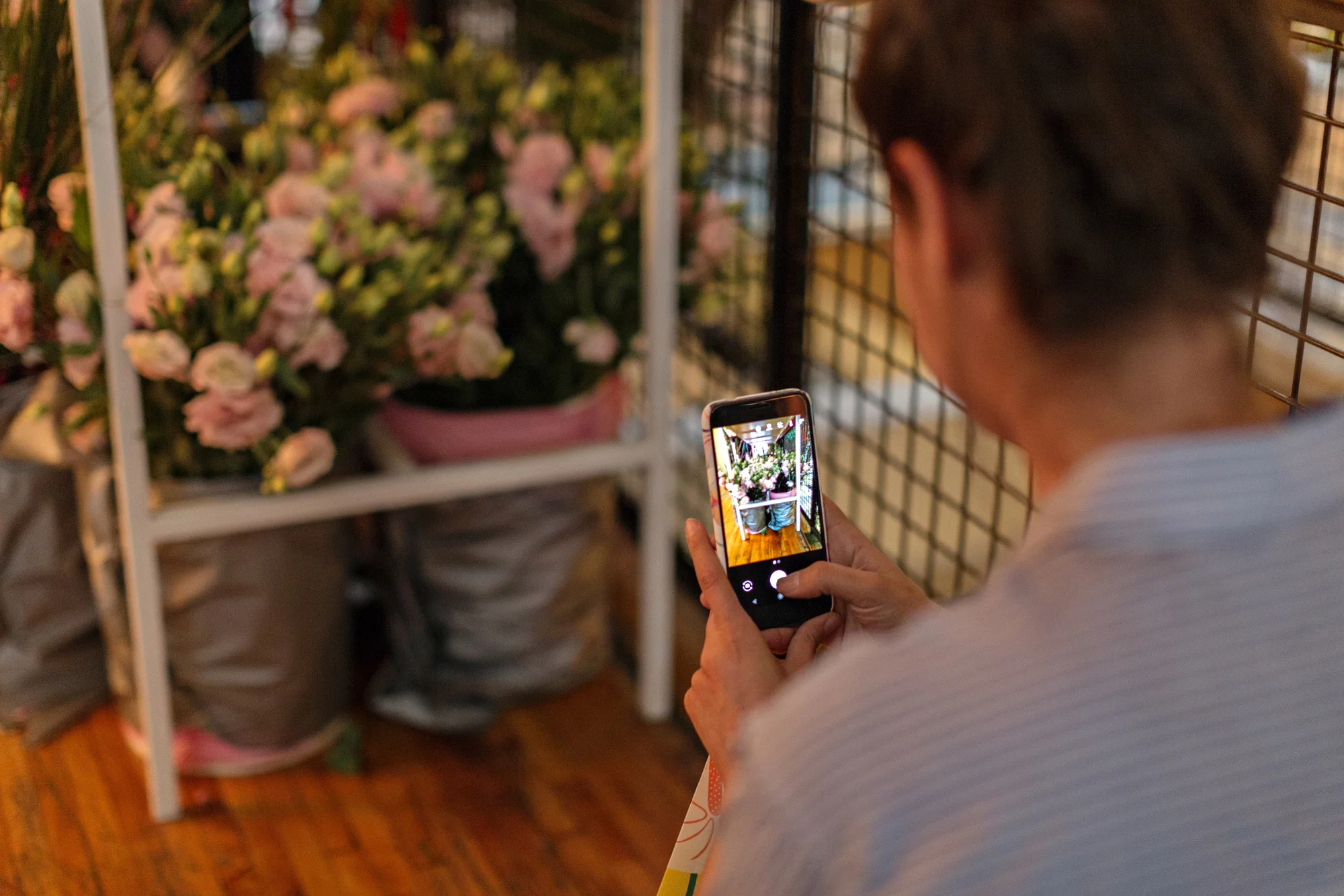 A person with a phone pointing at a flower arrangement