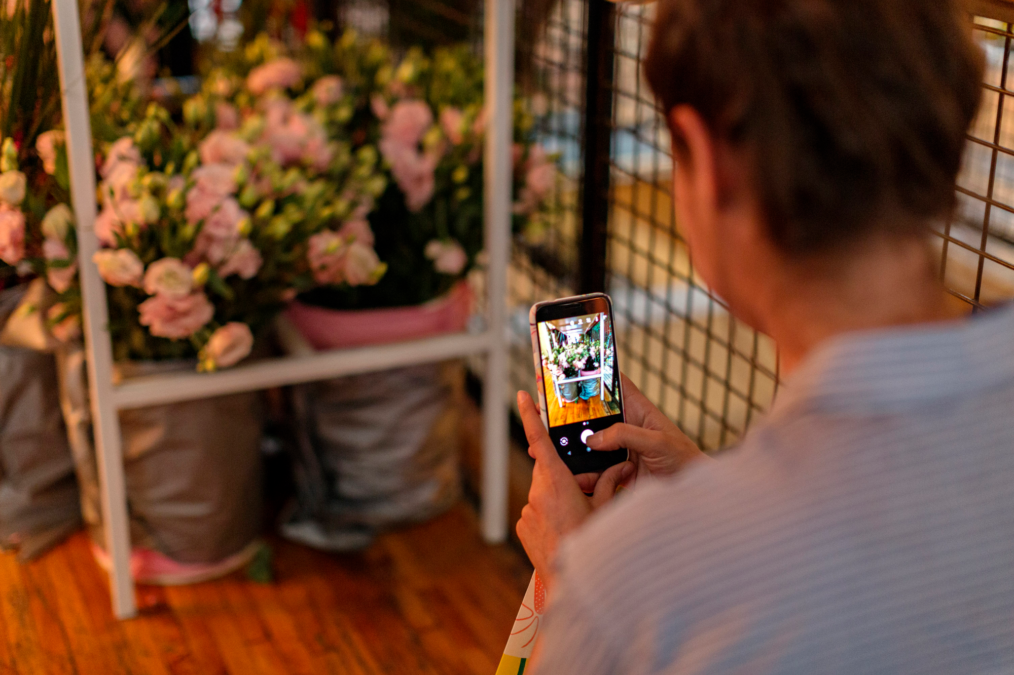 A person with a phone pointing at a flower arrangement