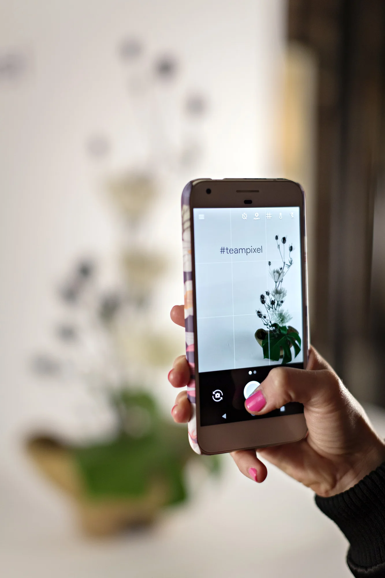 A phone pointing at a flower arrangement