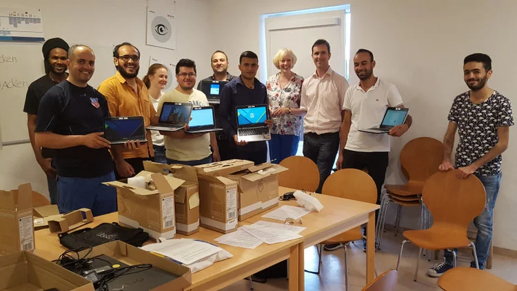 Foto auf dem eine Gruppe von Menschen zu sehen ist, die Chromebook-Laptops in den Händen halten.