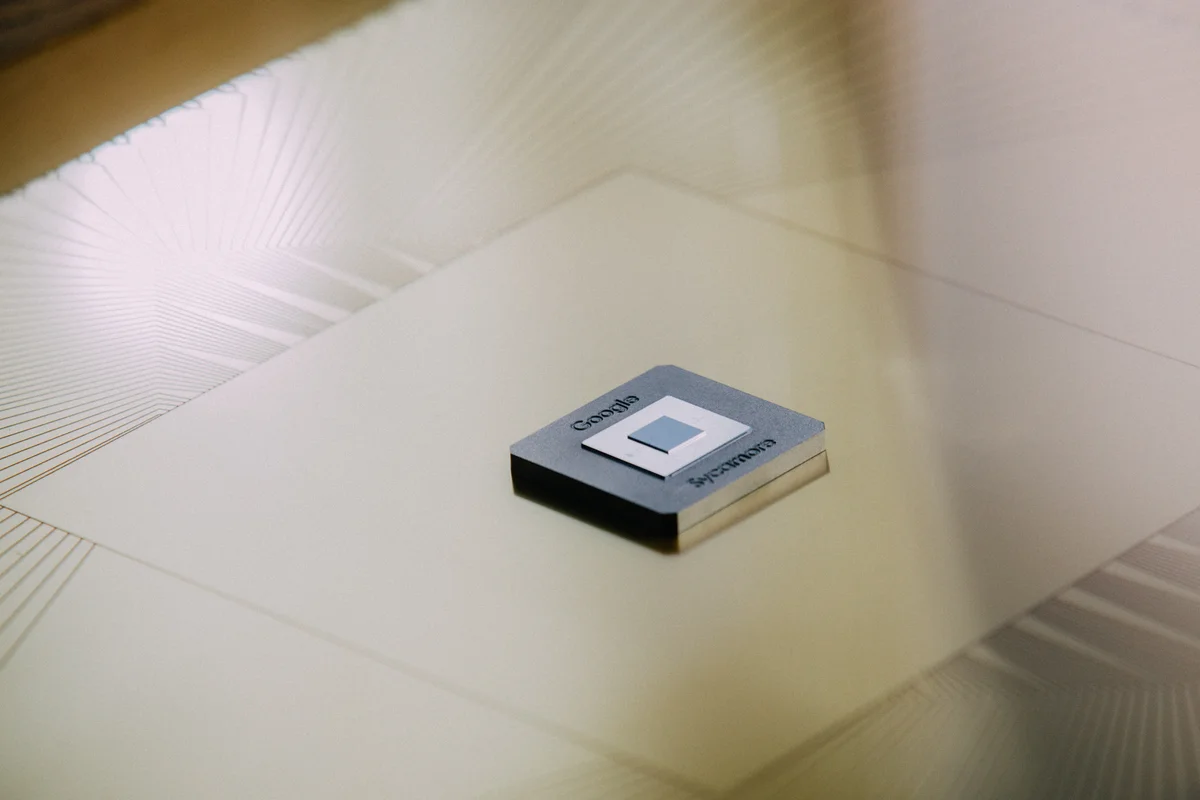 A picture of a processor chip with Google written on it, sitting on a metallic surface.