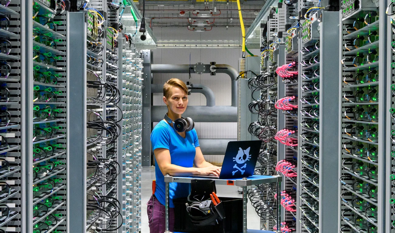 A Google employee working inside a data center with a laptop and headphones.