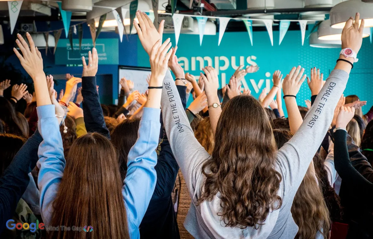 Group of young women seen from the back, raising their hands in joy