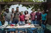 Eight people stand around a table outside and smile at the camera.