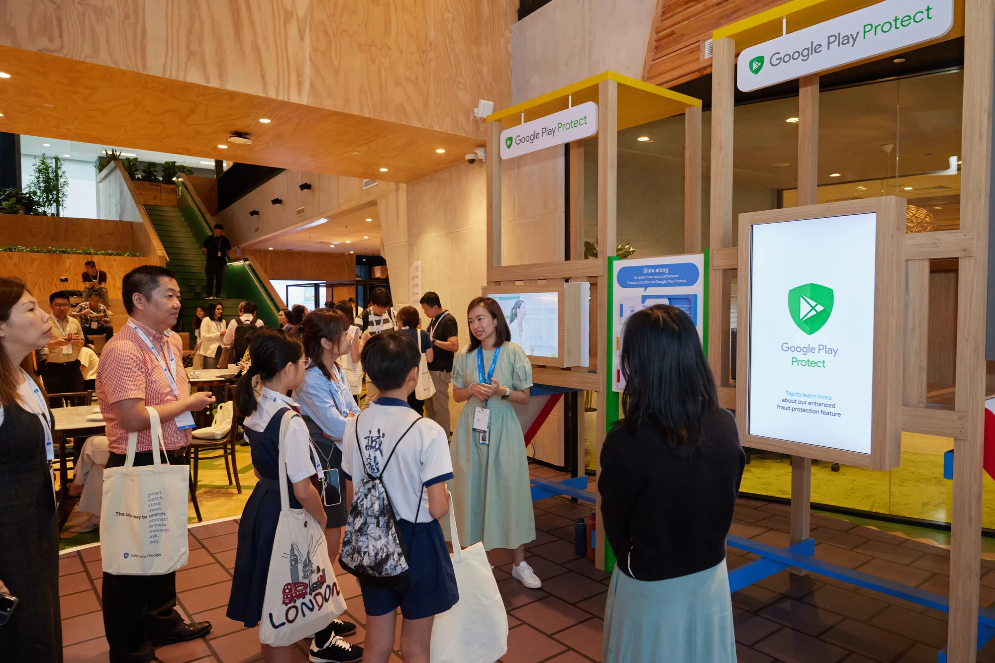 A group of people standing and looking at a screen that says "Google Play Protect"