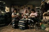 Three generations of women sit in a room weaving wool by hand
