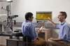 A photograph of Dr Angus Turner pointing at a computer screen showing retinal images – sitting with retinal specialist, Vaibhav Shah, at the Kimberley Hub, Broome.