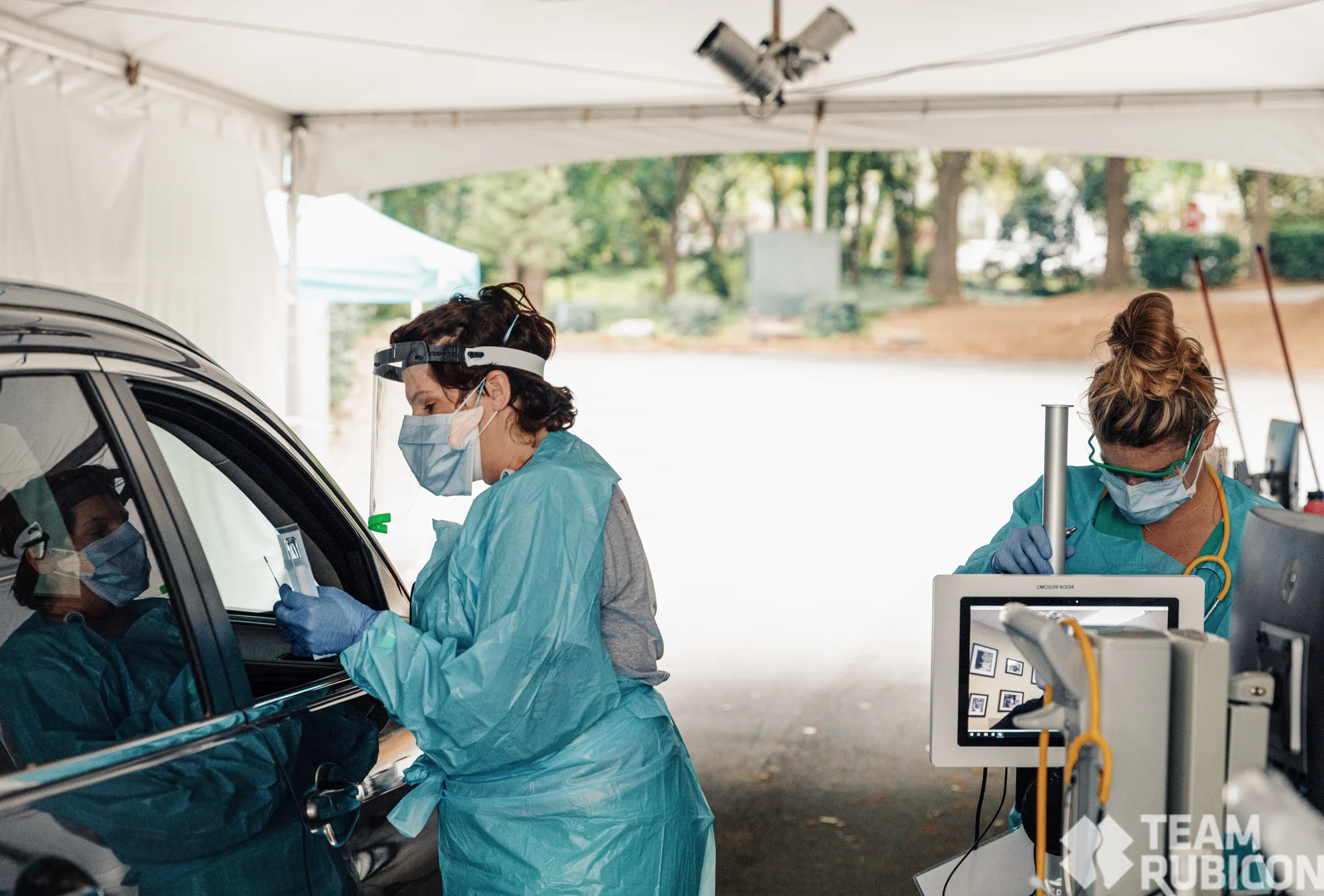 Two volunteers work at a drive-thru COVID testing site.