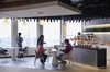 Googlers chat around circular tables in an office café in front of floor-to-ceiling windows with a view of Tokyo Tower.