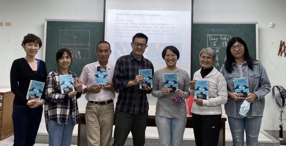 Seven men and women face the camera holding up books.