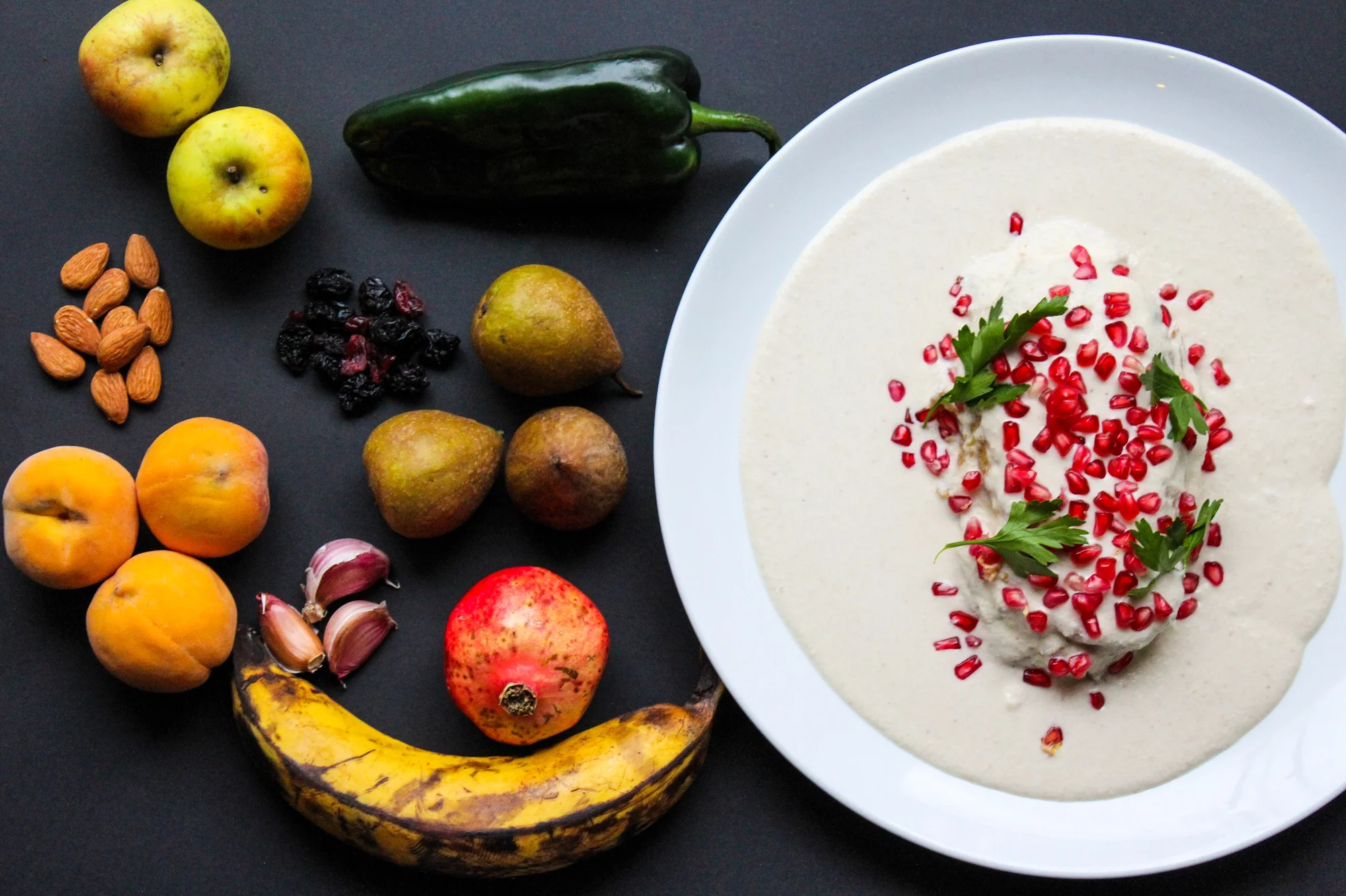 A variety of fruit laying on a table next to a Chile en Nogada dish