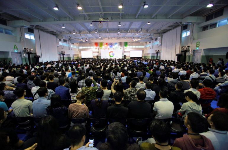 A room full of HTC colleagues looking towards a stage with a Google logo in the background, at their official welcome to Google Taiwan in 2018.