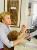 Angela sitting at a table working on a laptop with her fluffy brown puppy in her lap