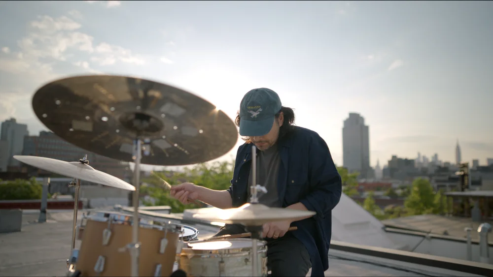 A person playing the drums in front of a city background