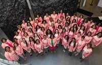 A photo of dozens of women wearing pink looking up at the camera