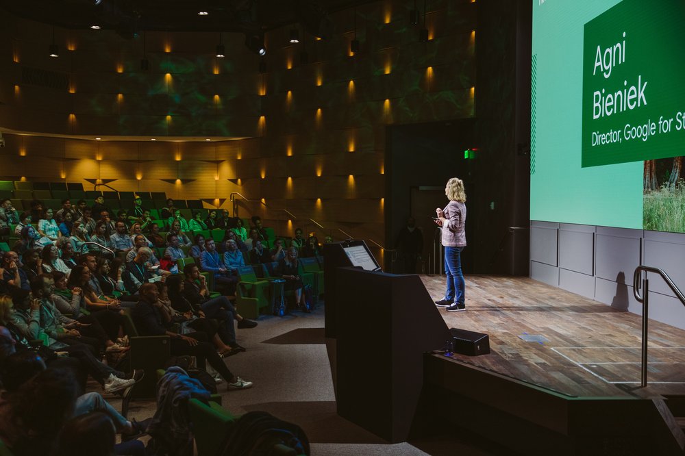 Agni standing on a stage, addressing an audience. Behind her is a slide that says “Agni Bieniek, Director Google for Startups.”