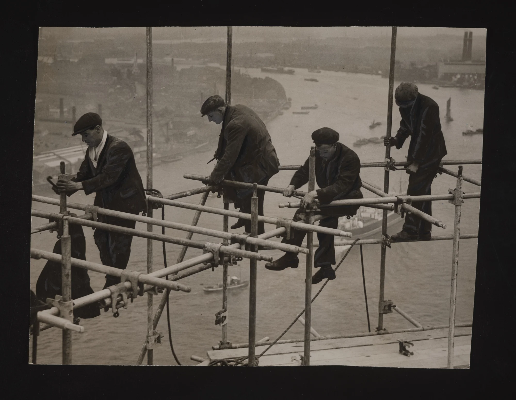 A black and white photograph of a group of steeplejacks working high above the ground