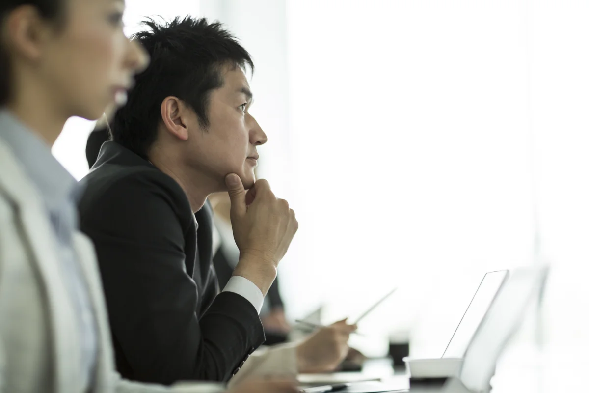 Alt text: Side-on image of a man and woman taking part in a digital skills class. They’re at the left of the image, looking towards the right of the image, with computers and papers in front of them.