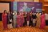 A group of 12 people standing and looking at the camera, in front of a backdrop that reads: “untold stories, a panel discussion on domestic violence”