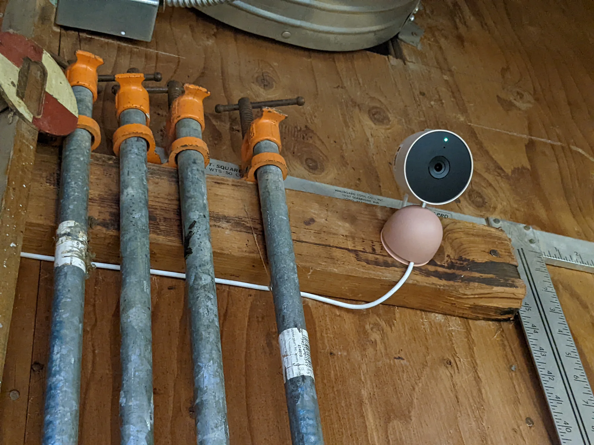 Nest Cam in the workshop, attached next to pipes against a wooden wall.