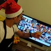 Asaf wears a santa hat and holds up a drink to toast with teammates virtually on a computer