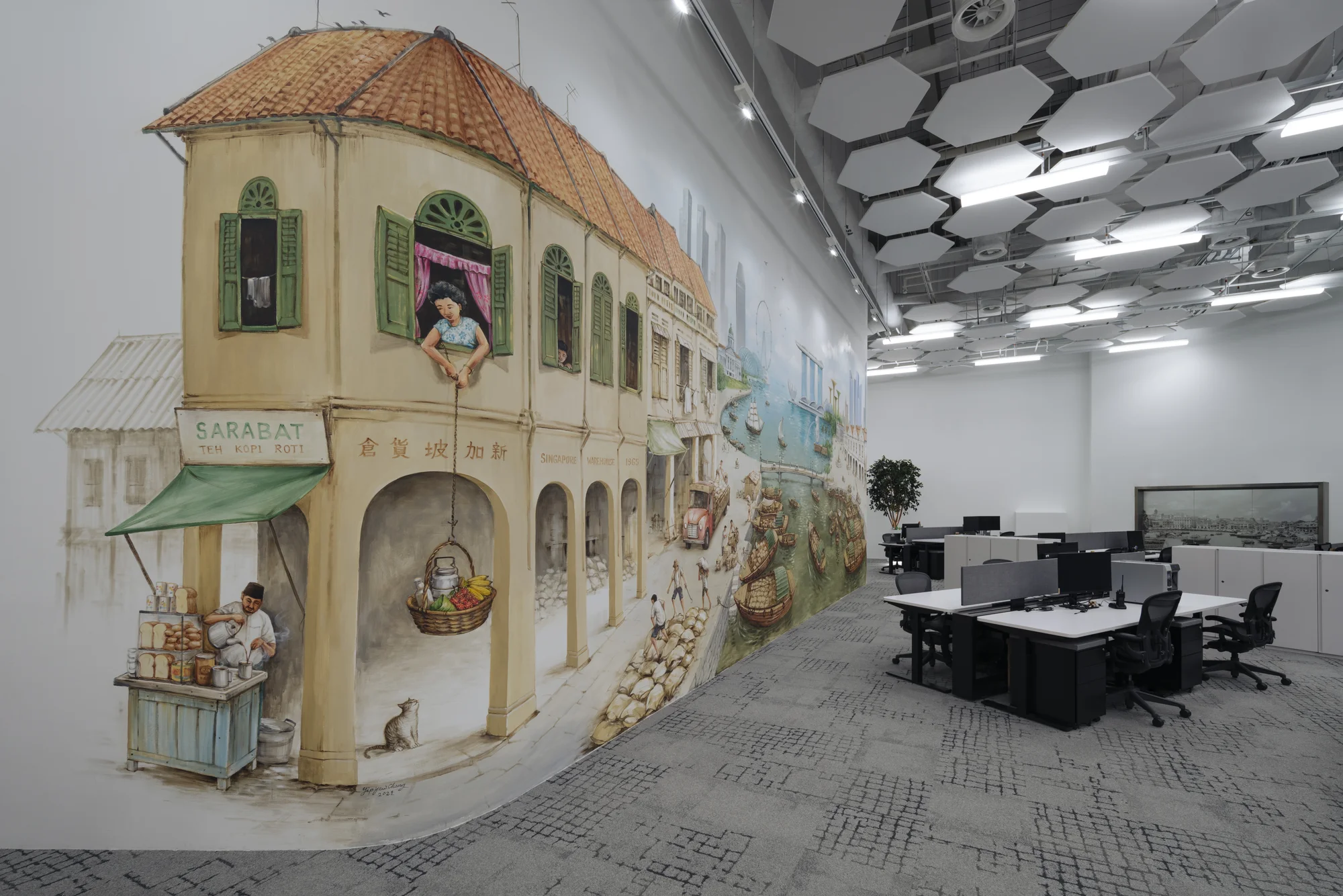 Indoor office space with desks, office chairs, and a large mural on the wall.