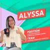 Photo of Alyssa holding a YouTube branded mug and doing a thumbs-up pose against a green and pink patterned background.
