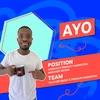 Photo of Ayo pointing to a YouTube branded mug against a patterned background of aqua blue and dark blue