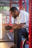 Will Smith resting between sets while sitting on a gym weight bench, wearing Fitbit Charge 4.