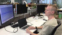 A man sitting in front of a computer screen studying data.