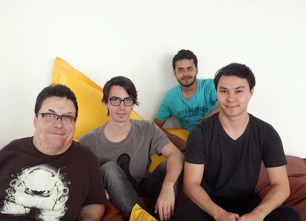 Four people sit on a large brown sofa.