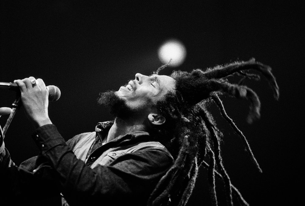 Black and white photo of Bob Marley singing at a microphone