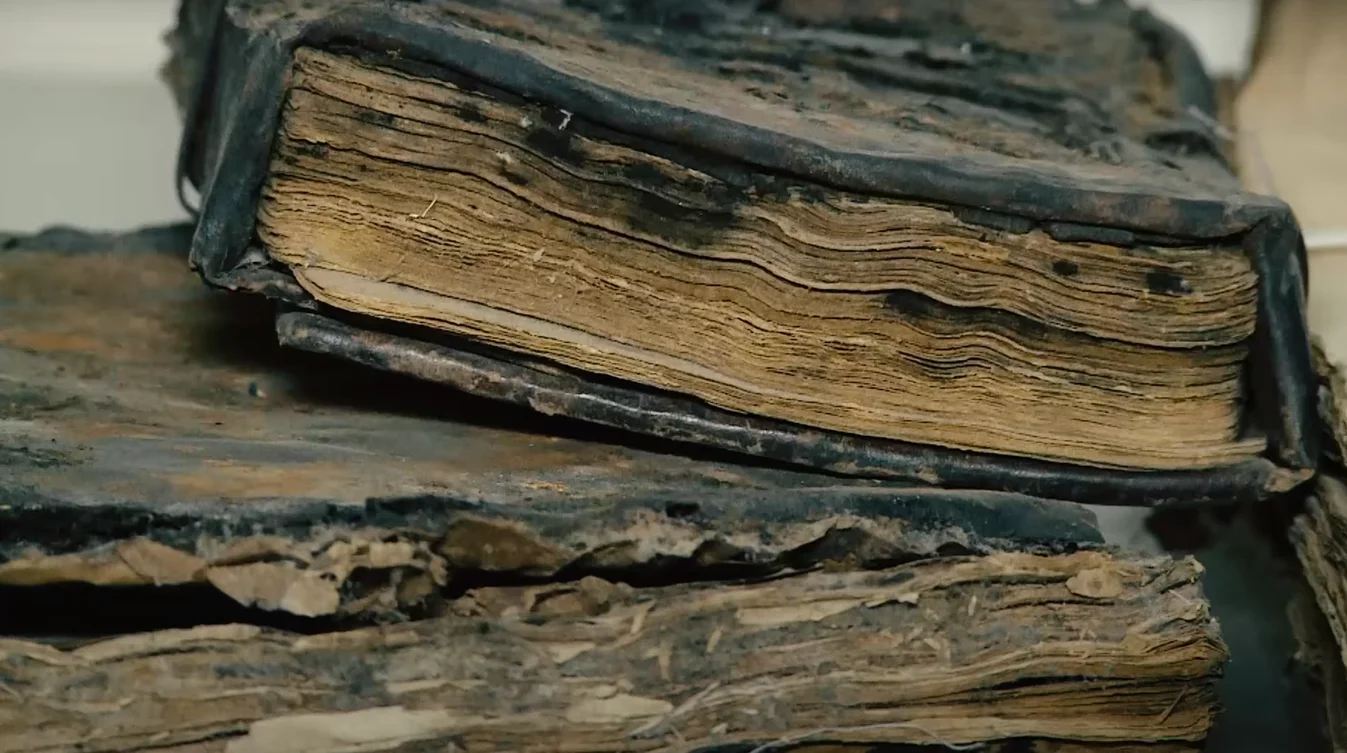 A stack of books containing ancient manuscripts.