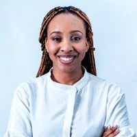 Photo of a lady wearing white, arms crossed over chest and looking into the camera with a smile