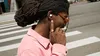 Person shown using the Pixel Buds Pro 2 at a crosswalk on a busy street.