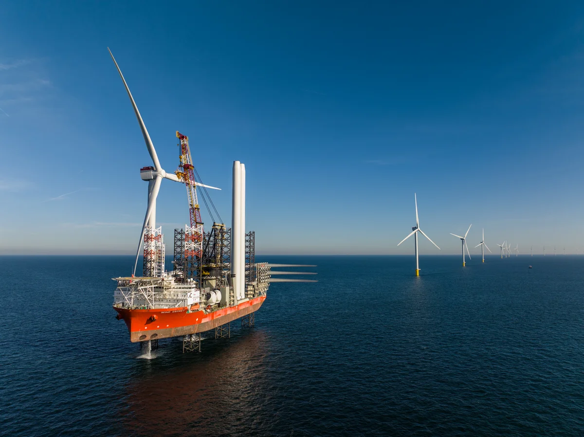 Een afbeelding van een schip naast windmolens.