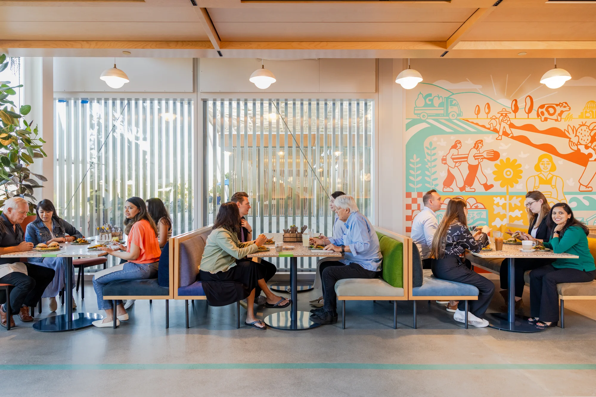 A photo of three booths with people eating and talking with each other.