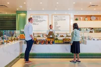 A photo of two people ordering food from a cafe team member at the counter of the cafe.