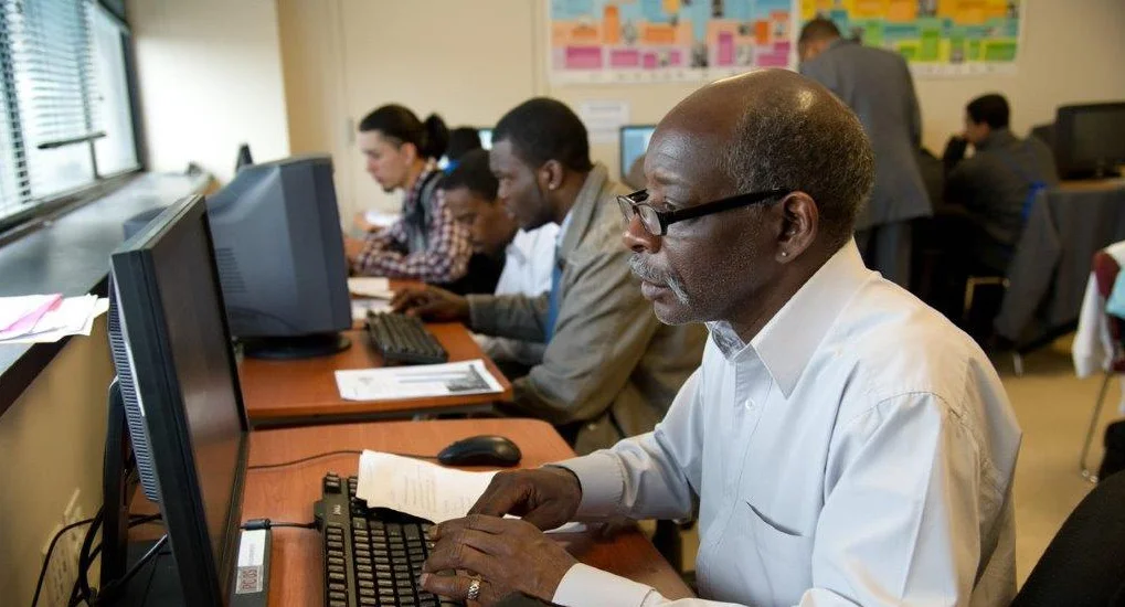 A group of people working at separate desktop computers.