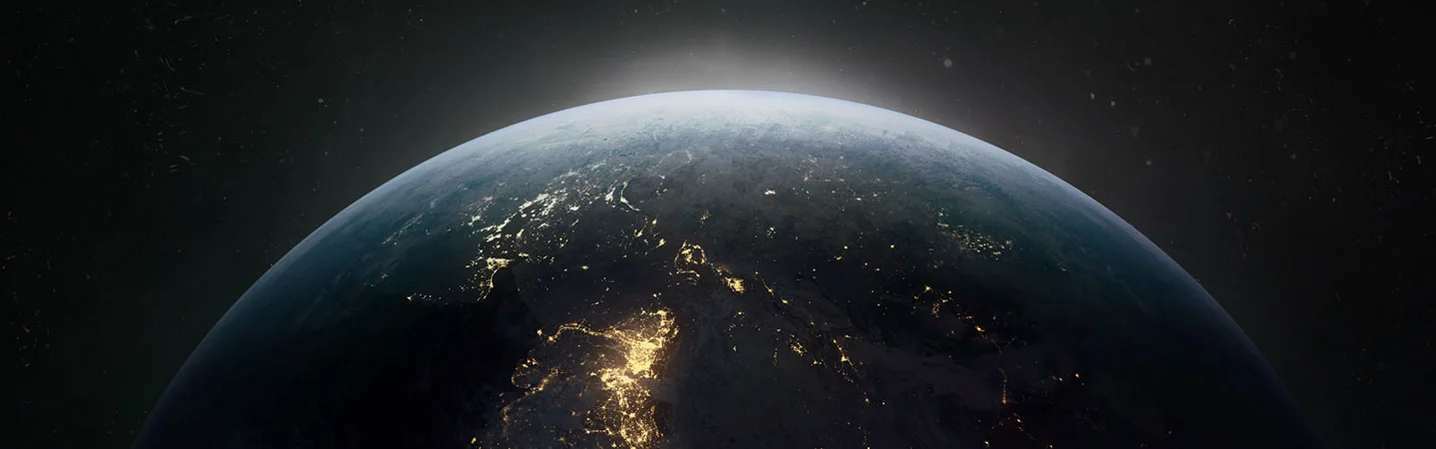 A photograph of roughly the top third of the globe taken from space. Various spots on the globe are lit up, indicating electricity use in highly populated areas.