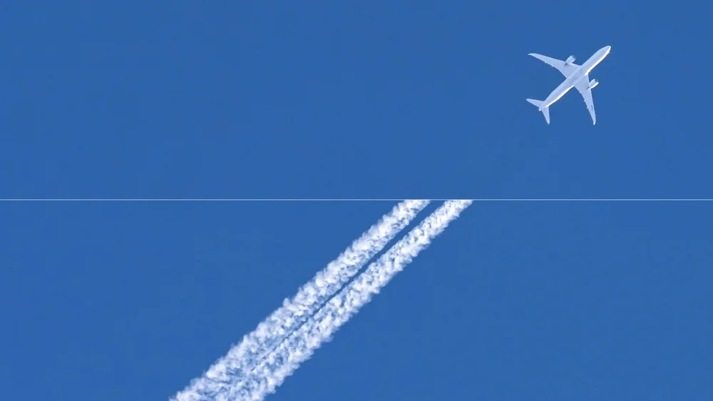 A plane flying through the sky, in half the image it's emitting a contrail, in the other half it is not showcasing the impact of our work.