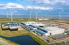 Ein Foto zeigt ein Google-Rechenzentrum mit Windrädern im Hintergrund bei Eemshaven, Niederlande