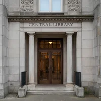 Der Eingang zu einem großen Steingebäude mit der eingravierten Aufschrift „Central Library“ über dem Eingang. Der Eingang ist von zwei Säulen eingerahmt und verfügt über einegroße Holztüre mit Glasscheiben.