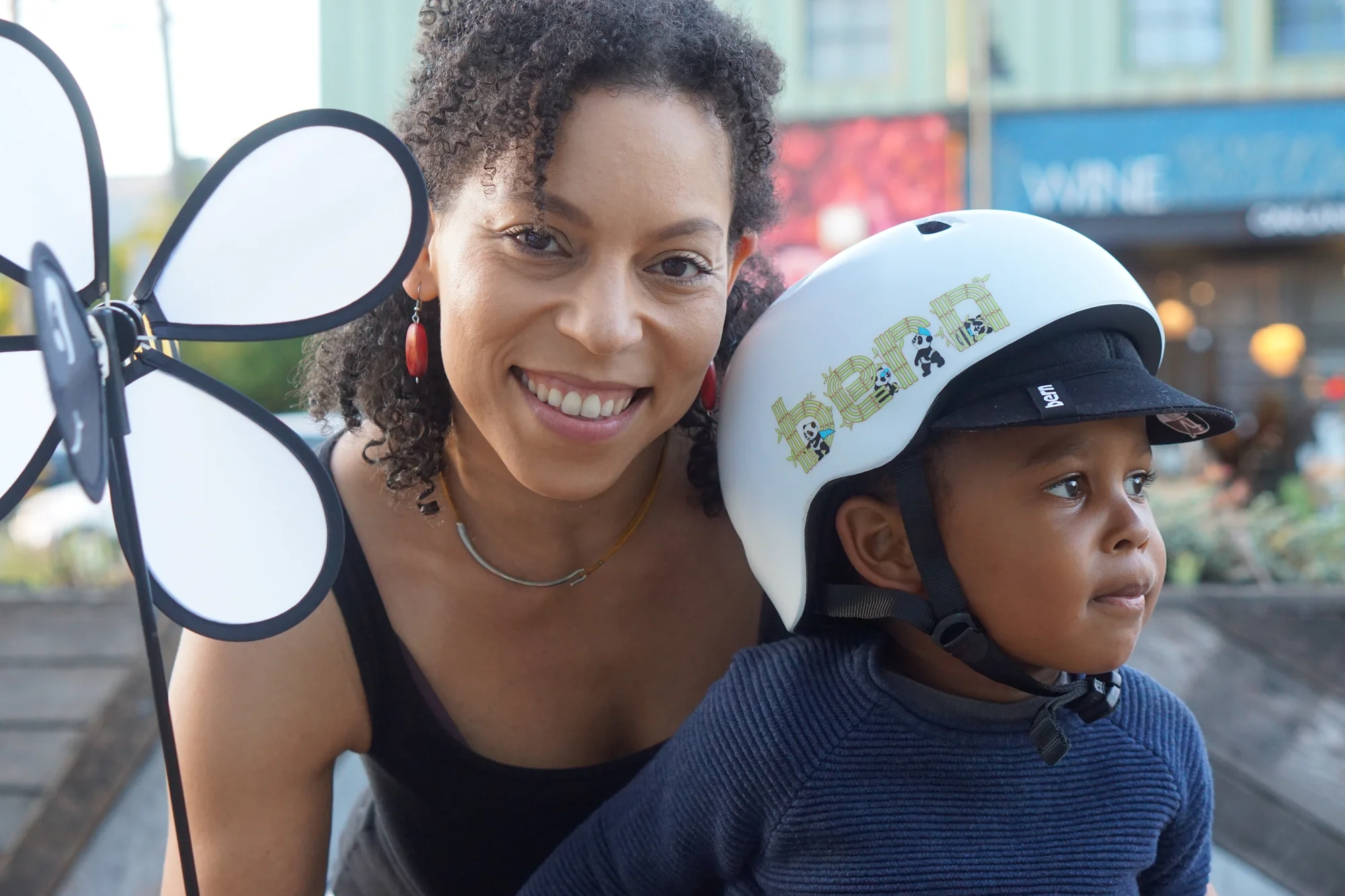 Victoria lächelt in die Kamera und hält ihren Sohn im Arm, der einen Fahrradhelm trägt