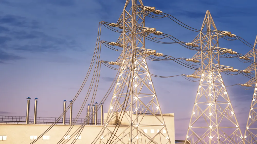 A photograph of two energy towers connected by wires and lit up in the dusk sky